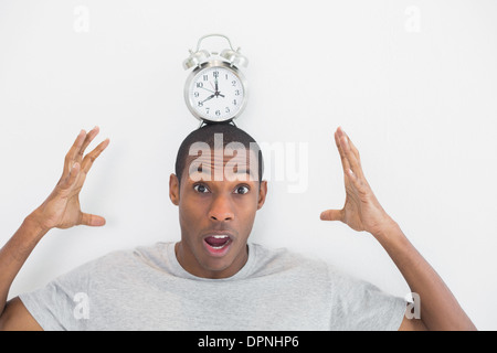 Shocked man with an alarm clock on top of his head Stock Photo