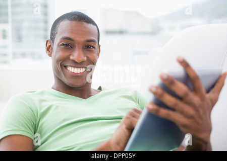 Casual smiling Afro man using digital tablet on sofa Stock Photo
