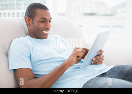 Casual smiling young Afro man using digital tablet on sofa Stock Photo