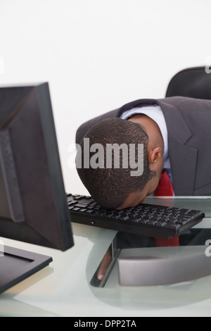 Afro businessman resting head on keyboard in office Stock Photo