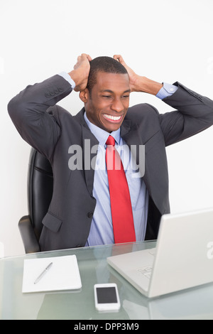 Frustrated Afro businessman looking at laptop at desk Stock Photo