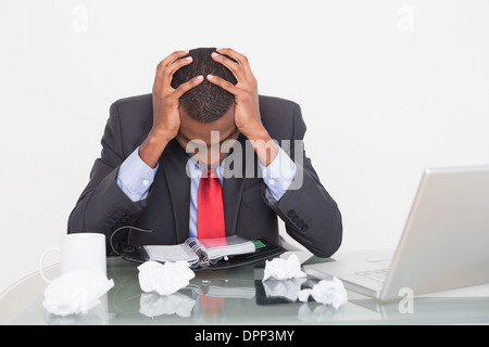 Frustrated Afro businessman with head in hands at  desk Stock Photo