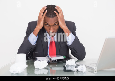 Frustrated Afro businessman with head in hands at  desk Stock Photo