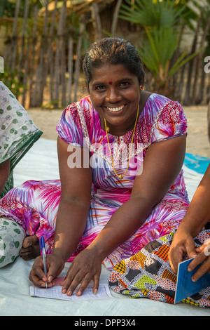 Woman of Akkini village filling out her savings book Savukkady, Chenkalady, Batticaloa District, Eastern Province, Sri Lanka. Stock Photo