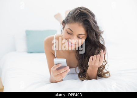 Smiling woman looking at mobile phone in bed Stock Photo