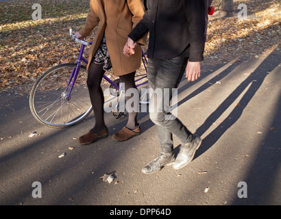 A couple holds hands as they walk in the late afternoon sun on Commonwealth Avenue Mall in Boston. Stock Photo