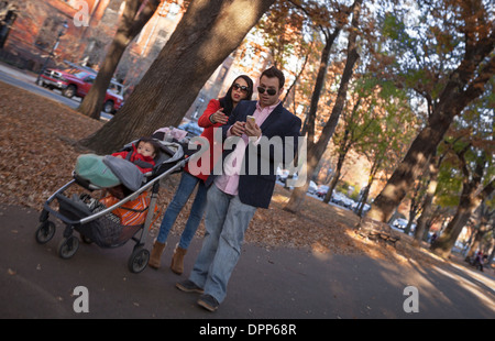 A couple and their child walk in the late afternoon sun on Commonwealth Avenue Mall in Boston. Stock Photo