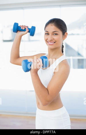 Woman exercising with dumbbells in fitness studio Stock Photo