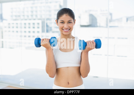 Woman exercising with dumbbells in fitness studio Stock Photo