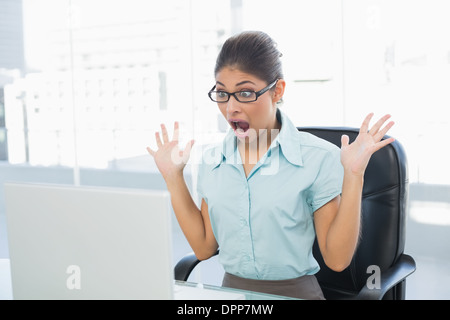 Shocked businesswoman looking at laptop in office Stock Photo