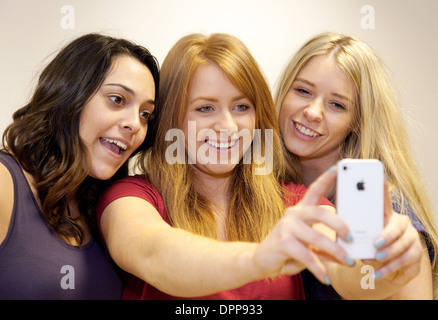 Selfie, being taken by three young women teenagers teens girls on an Apple iPhone, Essex UK Stock Photo