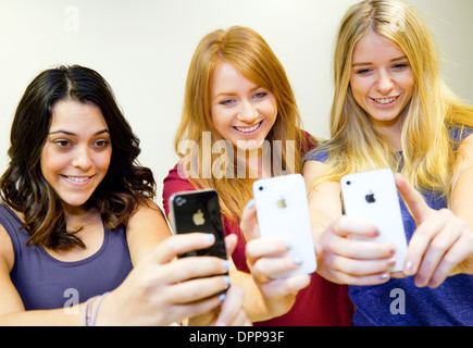 Three teenage girls taking a selfie with their 3 iphone5 mobile phones, Essex UK Stock Photo