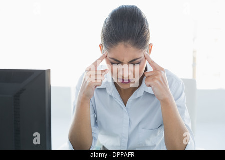 Tired businesswoman suffering from headache in front of computer Stock Photo