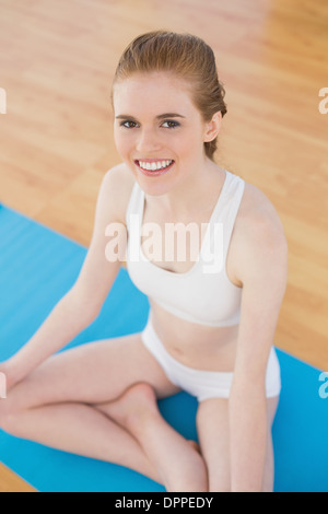 Smiling toned young woman sitting in lotus pose Stock Photo