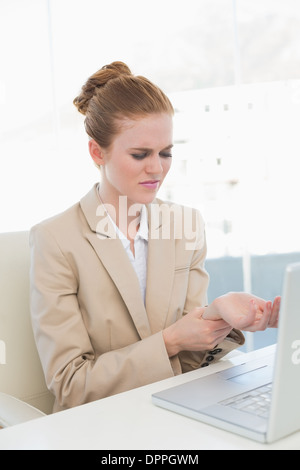 Businesswoman suffering from wrist pain in office Stock Photo