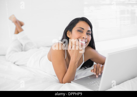 Relaxing woman lying on her bed using her notebook Stock Photo