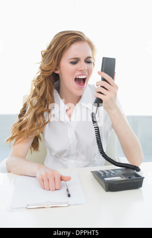 Businesswoman shouting into the phone at office Stock Photo