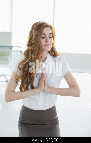 Worried elegant businesswoman joining hands in office Stock Photo