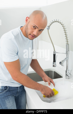 Young man doing the dishes at kitchen sink Stock Photo