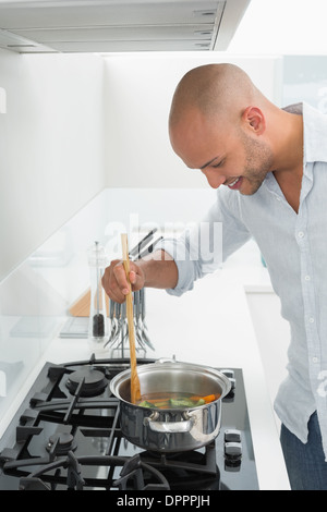 Side view of smiling man preparing food in kitchen Stock Photo