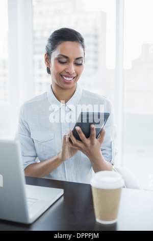 Content businesswoman using a calculator sitting at her desk Stock Photo