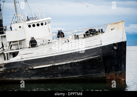 The wreck of the Saint Christopher (HMS Justice) aground in the harbor of Ushuaia, Argentina. The Sain Christopher is an American-built rescue tug that served in the British Royal Navy in World War II. After the war she was decommissioned from the Royal Nay and sold for salvage operations in the Beagle Channel. After suffering engine problems in 1954, she was beached in 1957 in Ushuaia's harbor where she now serves as monument to the shipwrecks of the region. Stock Photo