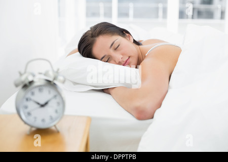 Sleeping woman with blurred alarm clock on bedside table Stock Photo