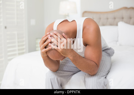 Thoughtful bald man with head in hands on bed Stock Photo