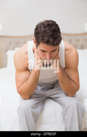 Thoughtful young man sitting in bed Stock Photo