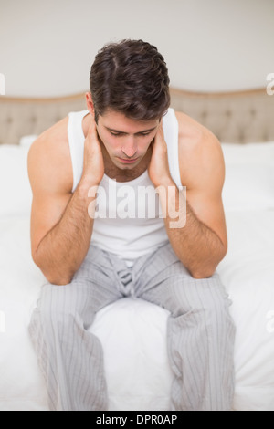 Thoughtful young man sitting in bed Stock Photo