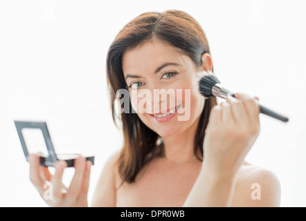 attractive woman in her forties applying makeup Stock Photo