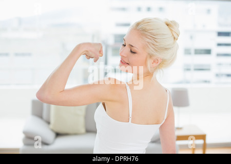 Rear view of fit woman flexing muscles in fitness studio Stock Photo