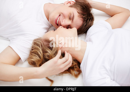 Two happy young dates lying in bed and looking at one another Stock Photo