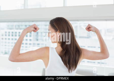 Fit brown haired woman flexing muscles in fitness studio Stock Photo