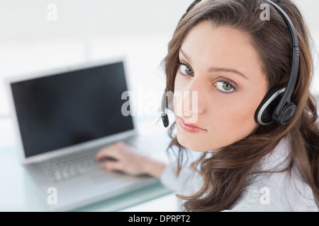 Serious businesswoman wearing headset in front of laptop Stock Photo