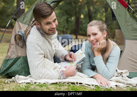 Smiling couple with a map lying in tent Stock Photo