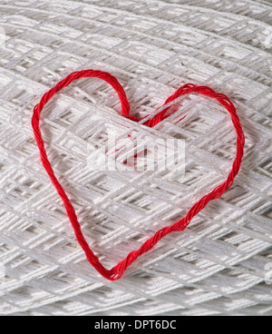 Knitted red heart on white ball of yarn. Stock Photo