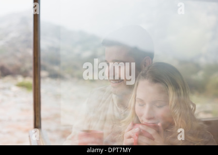 Thoughtful couple with coffee cups seen through cabin window Stock Photo