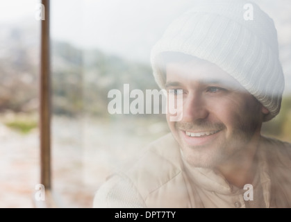 Thoughtful smiling man looking out through window Stock Photo