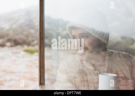 Thoughtful man with cup looking out through window Stock Photo