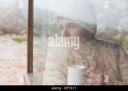 Thoughtful man with cup looking out through window Stock Photo
