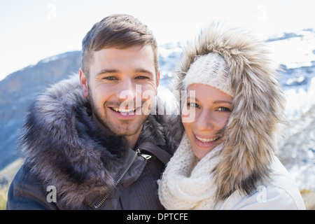 Loving couple in jackets against snowed mountain Stock Photo