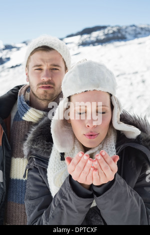 Couple with cupped hands on snow covered landscape Stock Photo