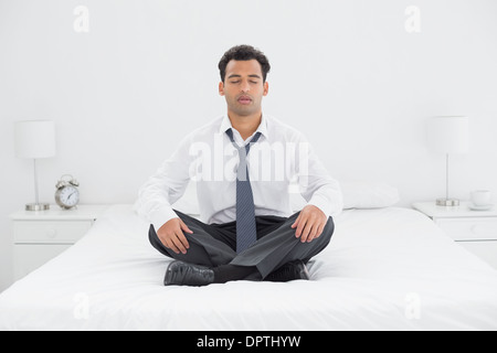 Relaxed well dressed man sitting with eyes closed on bed Stock Photo