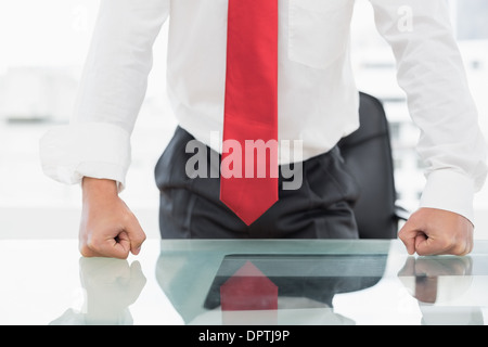 Mid section of a businessman with clenched fists on desk Stock Photo