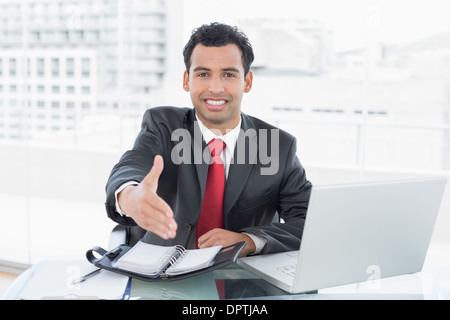 Businessman offering a handshake at office desk Stock Photo