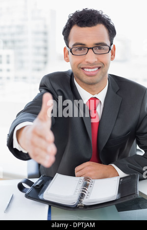 Businessman offering a handshake at office desk Stock Photo