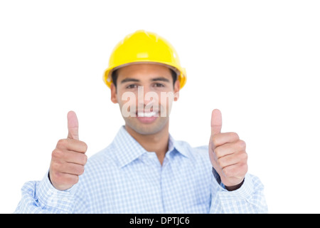 Smiling handyman in yellow hard hat gesturing thumbs Stock Photo
