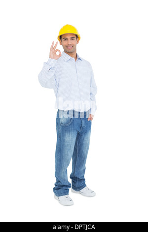 Smiling handyman in yellow hard hat gesturing okay sign Stock Photo