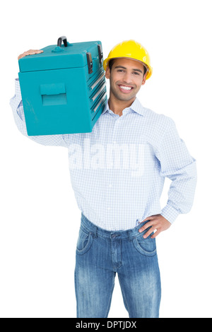 Portrait of a smiling handyman in hard hat carrying a toolbox Stock Photo
